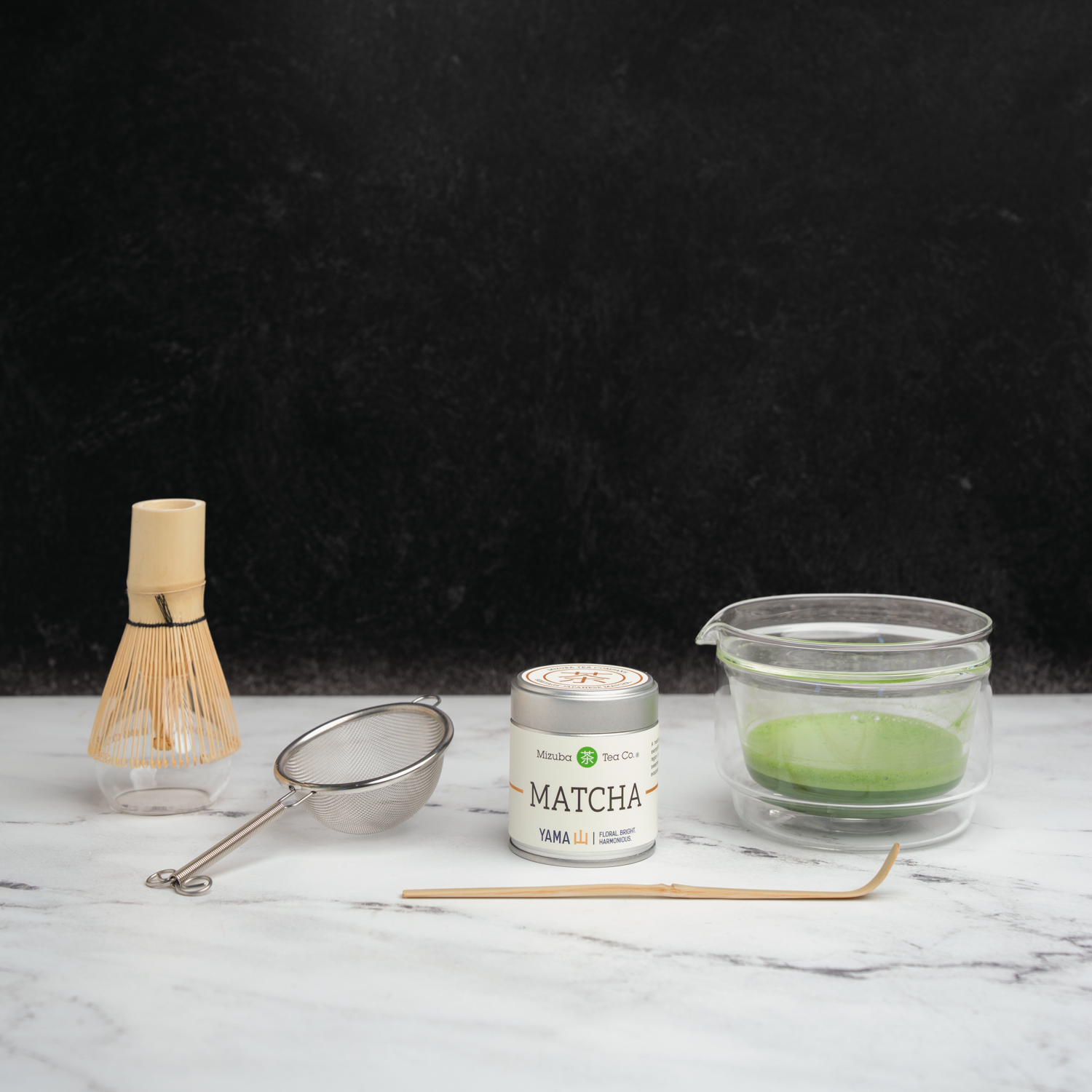 Matcha green tea powder tin with tea tools next to it