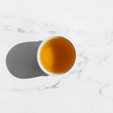 A top down view of green tea in a white cup on a white table