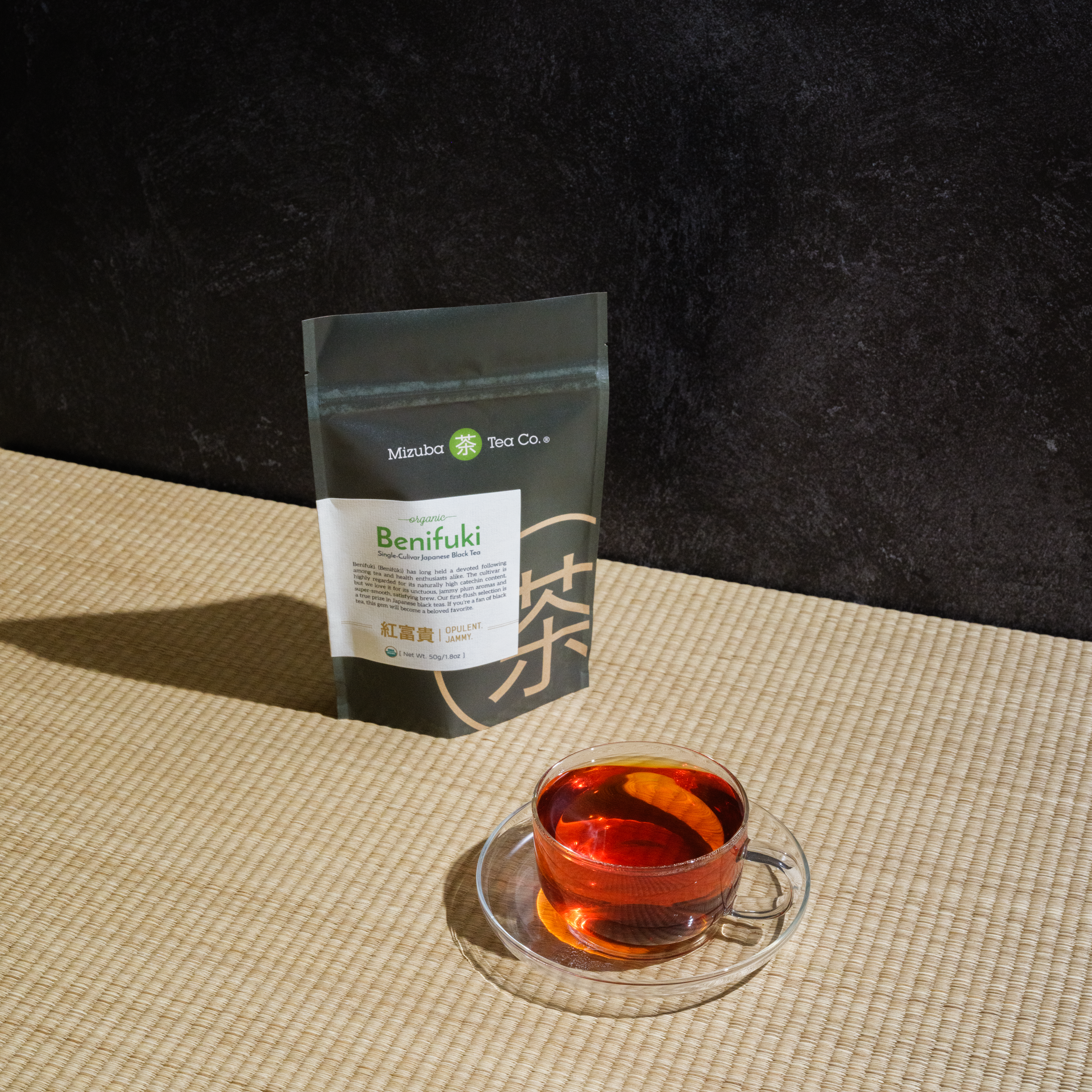 Benifuki from Mizuba Tea on a textured table with a glass of brewed green tea