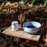 Mizuba Matcha green tea tin container, whisk, and bowl on a mat with a natural background
