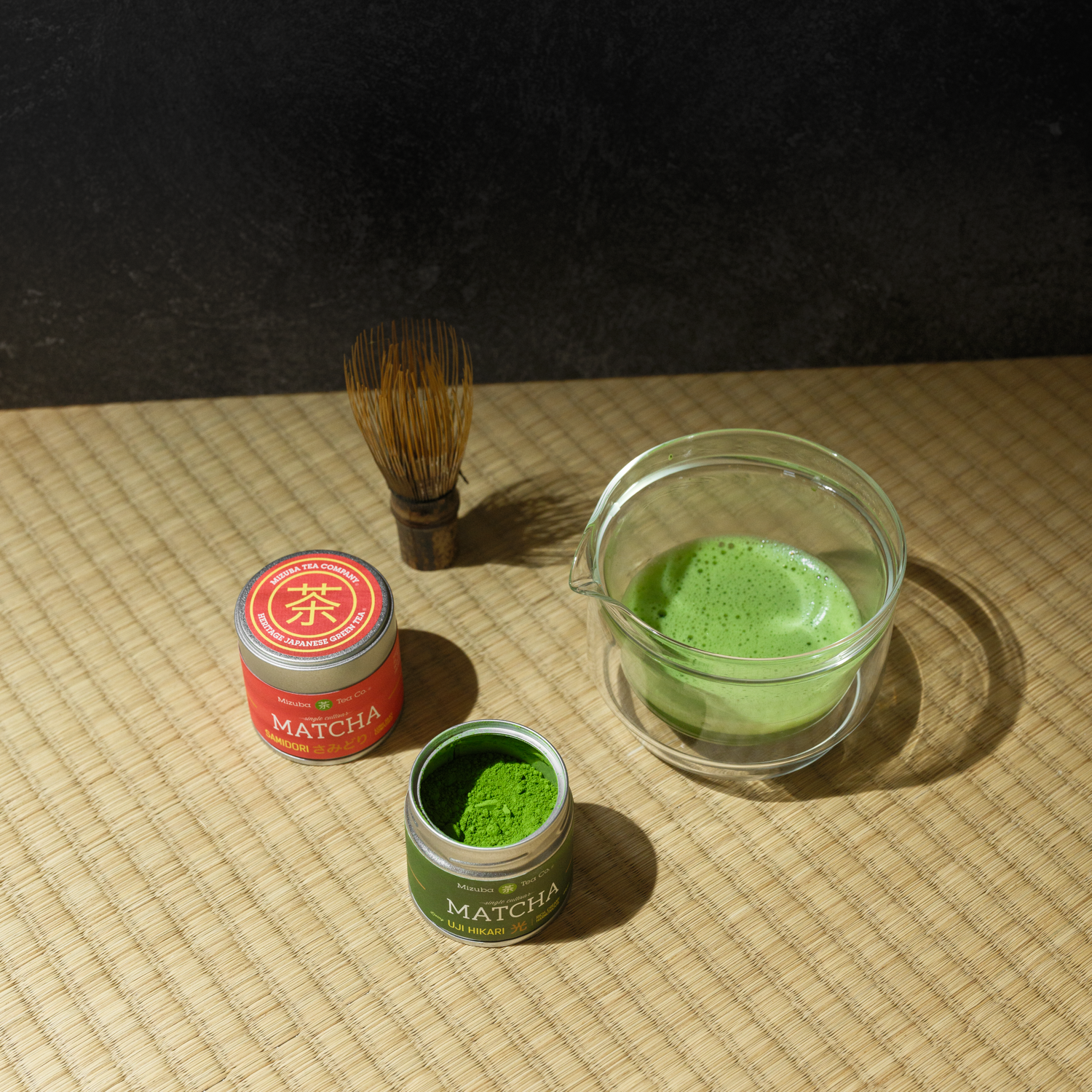 Samidori and Uji Hikari matcha tins next to each other with brewed match and a chasen