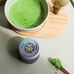 Matcha powder next to Mizuba Tin and brewed green tea