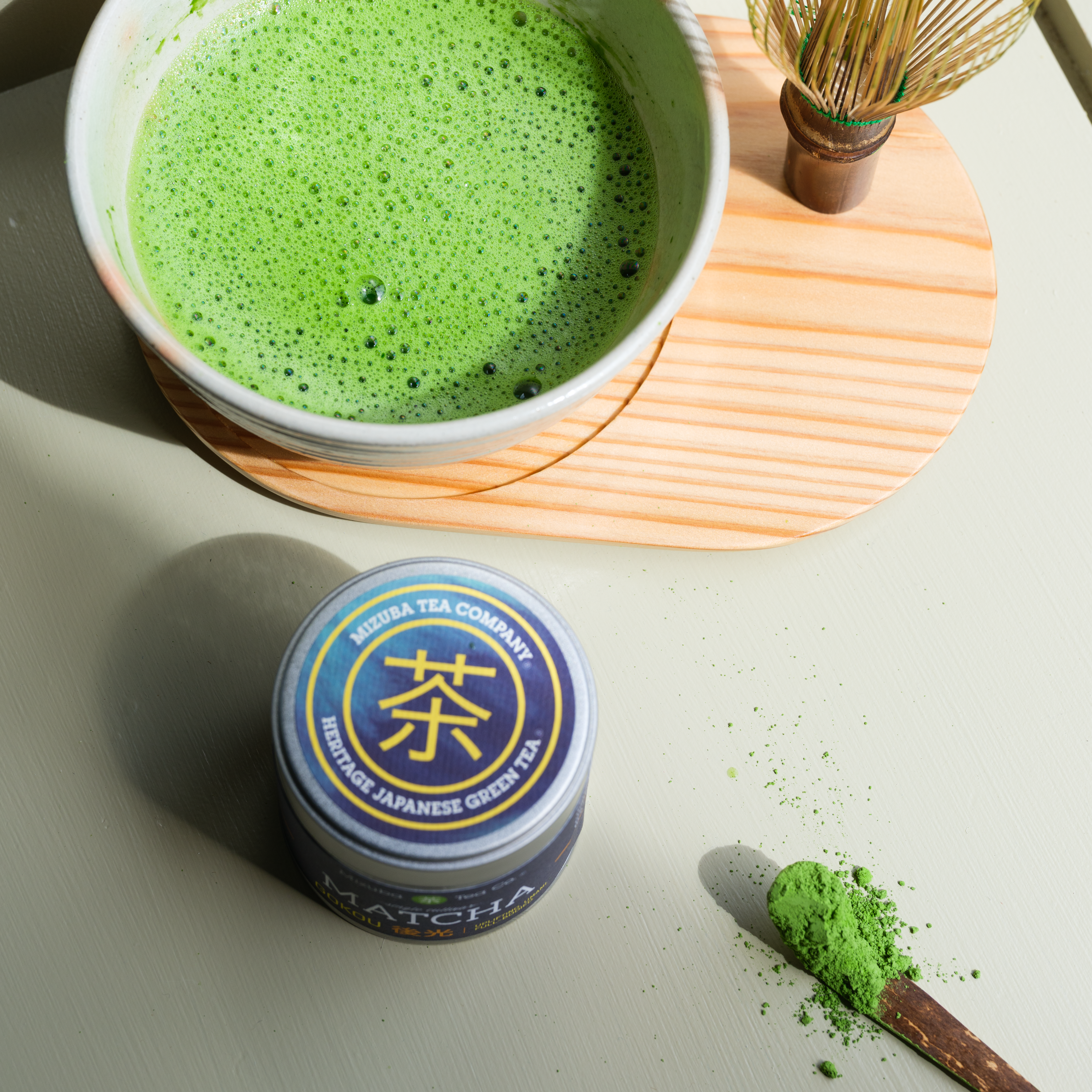 Matcha powder next to Mizuba Tin and brewed green tea
