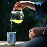 Pouring fresh 2025 Japanese shincha green tea into a Asemi yunomi blue ceramic cup. 