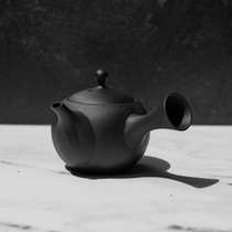 Black tea pot on a white surface