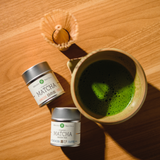 Mizuba Matcha green tea canisters and a cup of matcha on a wooden surface
