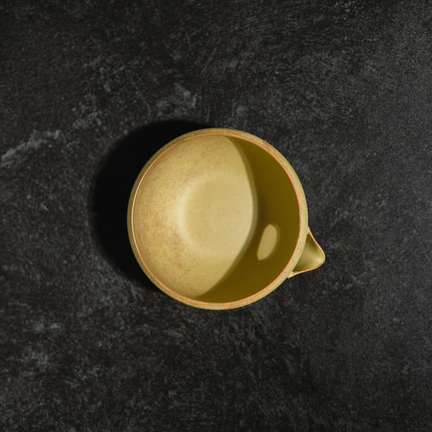 Yellow ceramic chawan matcha bowl by Origami on a dark textured surface