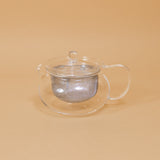 Japanese glass tea pot by Hario sits on a yellow background