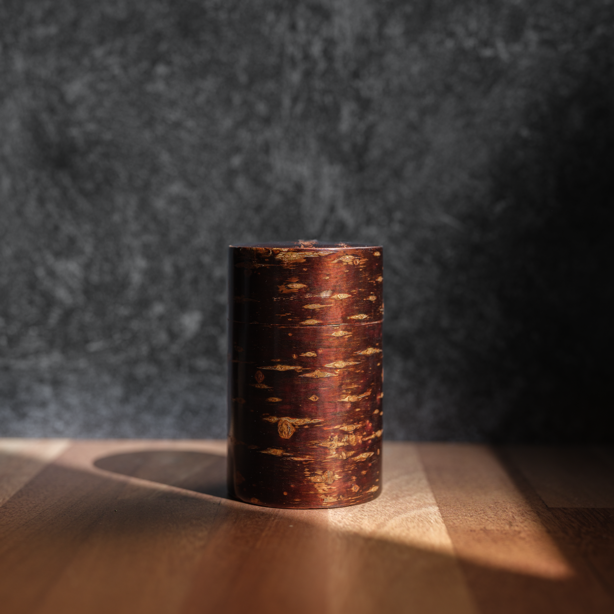 A tall cansiter wrapped in cherrywood for storing tea. 