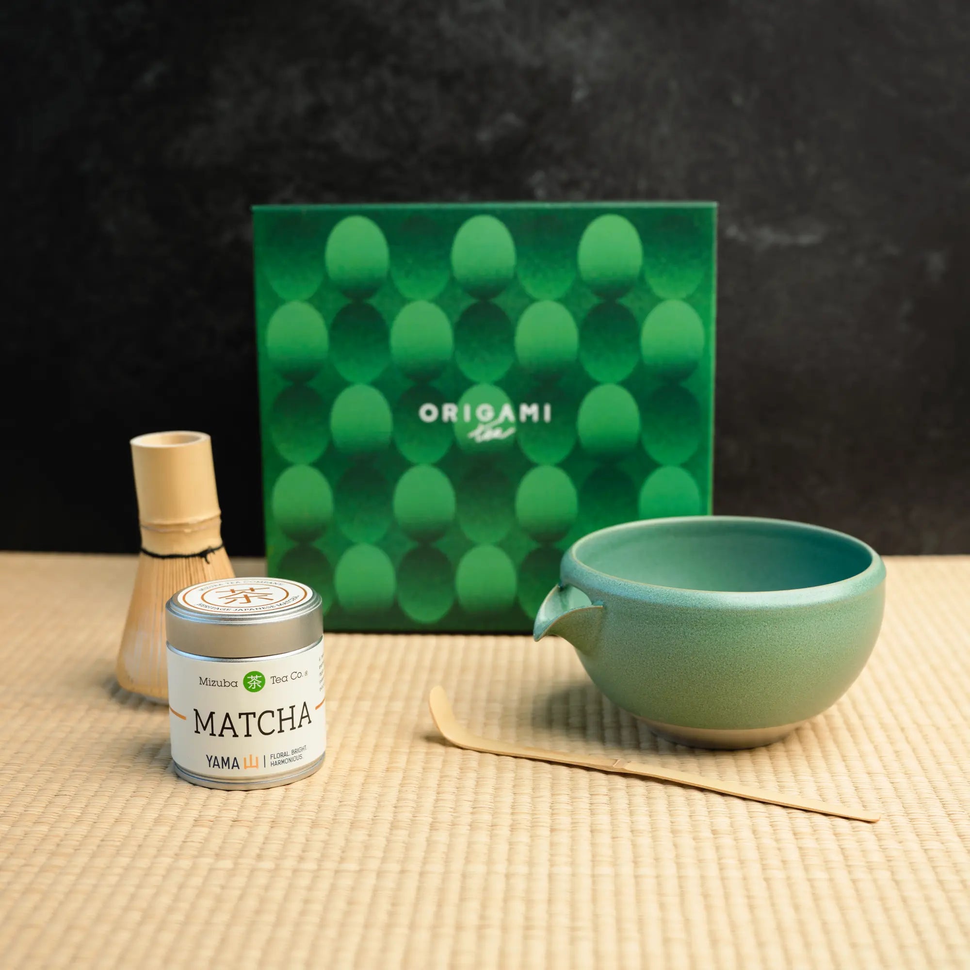 Mizuba Matcha tin next to a chasen, chawan, and matcha bowl