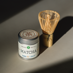 Mizuba Yama Matcha tea canister with a chasen whisk on a gray surface
